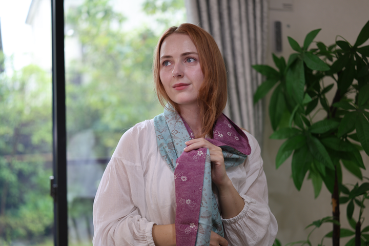 A model wearing the pale blue and purple double-sided silk stole at a dark table.
