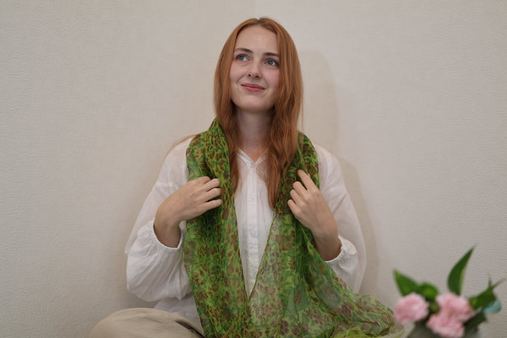 A model holding the two hanging sides of the green Edo Sarasa silk stole in a quiet Japanese room.