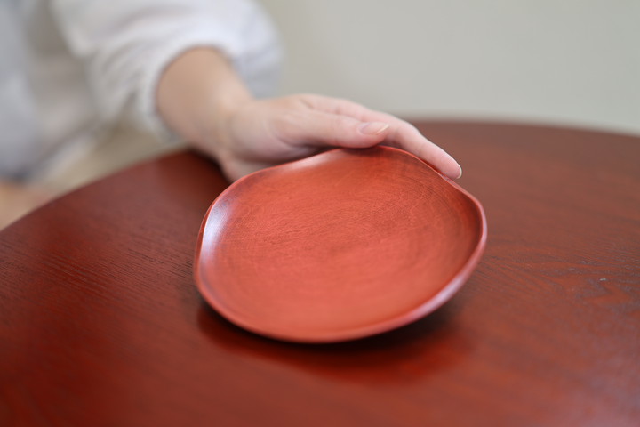 RIN 5.0 Berry on a red lacquered table with a person's hand reaching toward the plate.