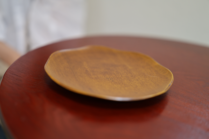 RIN 7.0 Mimosa plate resting on a red lacquered table with a seated model partially visible at the edge of the frame.