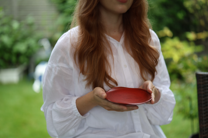 Seated person holding RIN 5.0 Berry in a shaded garden setting.