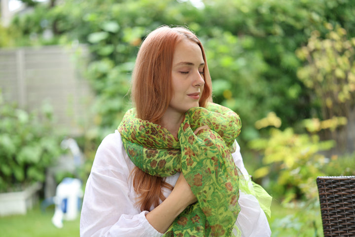 A model wearing the green Edo Sarasa silk stole high around her neck in soft garden light.