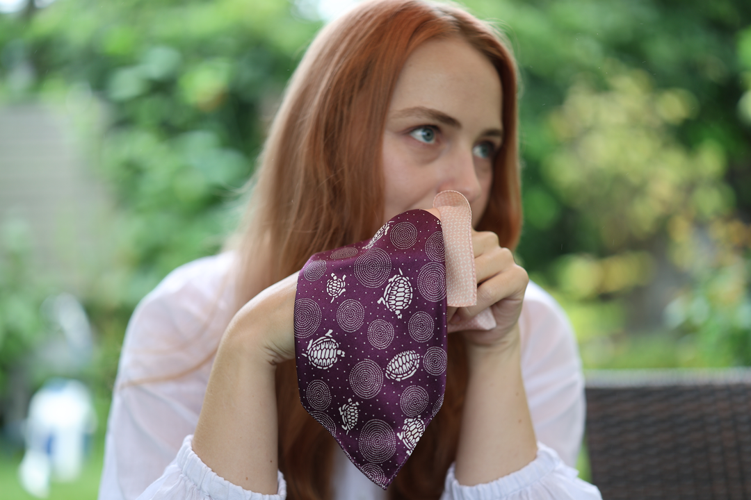 A model holding the Edo-purple and cherry-blossom-pink silk pocket square outdoors.