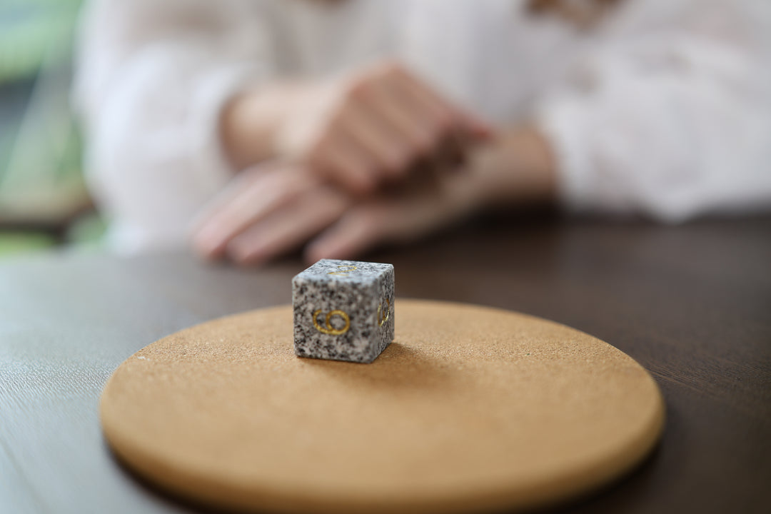 Makabe Stone Master Die resting on a protective ochre cloth in a quiet indoor setting.