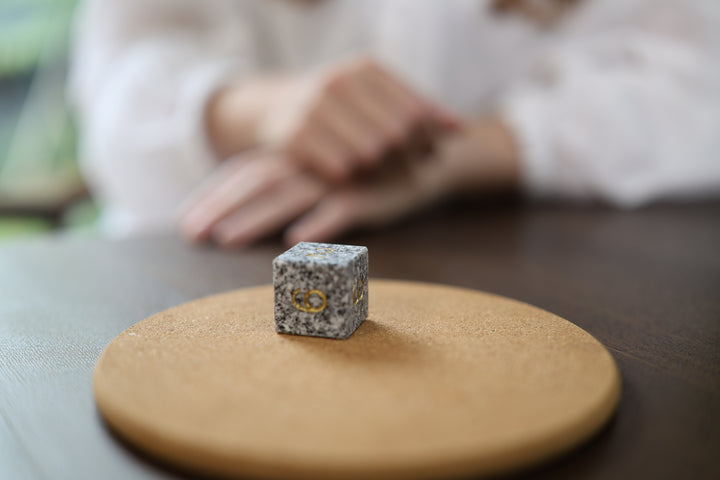 Makabe Stone Master Die resting on a protective ochre cloth in a quiet indoor setting.