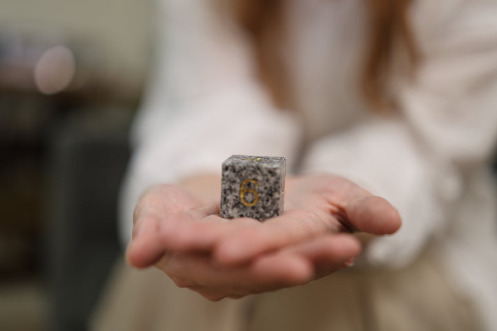 Makabe Stone Master Die held in an open palm for a close view of its scale and mineral grain.