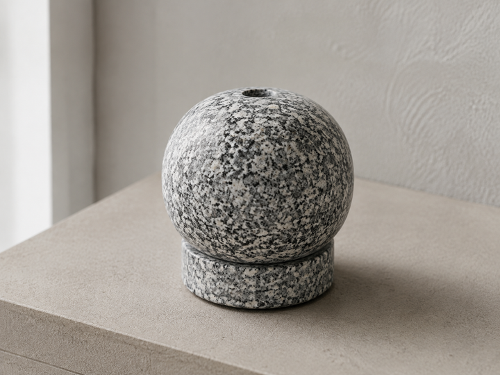 Close daylight view of the gray-white Makabe granite grain across the rounded incense holder.