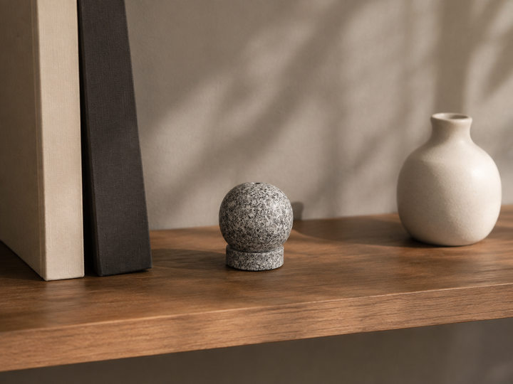 Makabe Stone Incense Stone displayed with spaced books and a ceramic object on a calm shelf.
