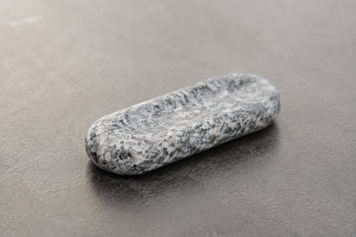 Close view of the gray, white, and black crystalline grain of a Makabe stone cutlery rest.