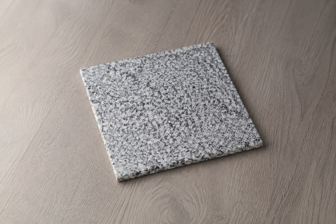 The square Makabe Stone Art Plate displayed alone in soft side light, revealing its natural mineral grain and thin edge.