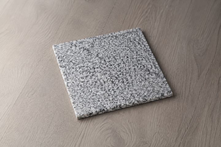 The square Makabe Stone Art Plate displayed alone in soft side light, revealing its natural mineral grain and thin edge.