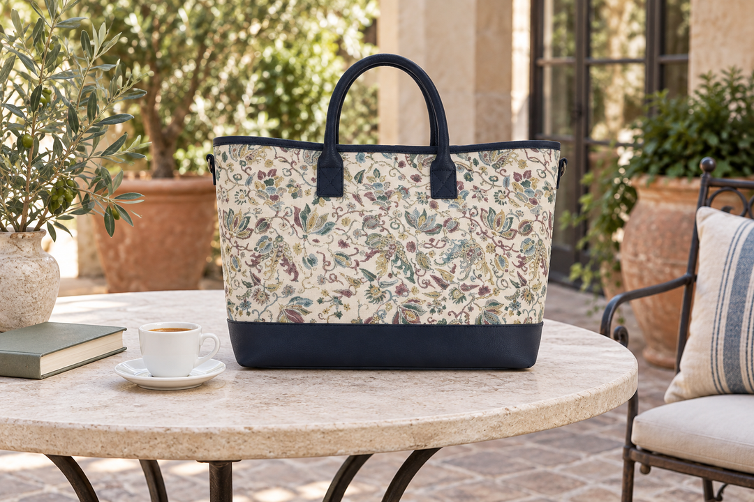 The navy floral Edo Sarasa tote on a round table beside a coffee cup, a book, and potted greenery.