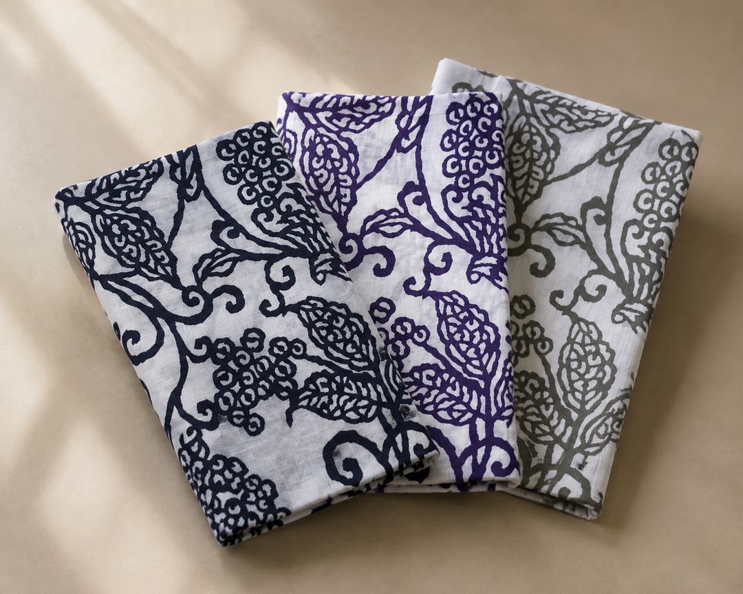 Close view of the visible arabesque pattern and cotton weave on a dark-blue tenugui, with the other two colorways behind.