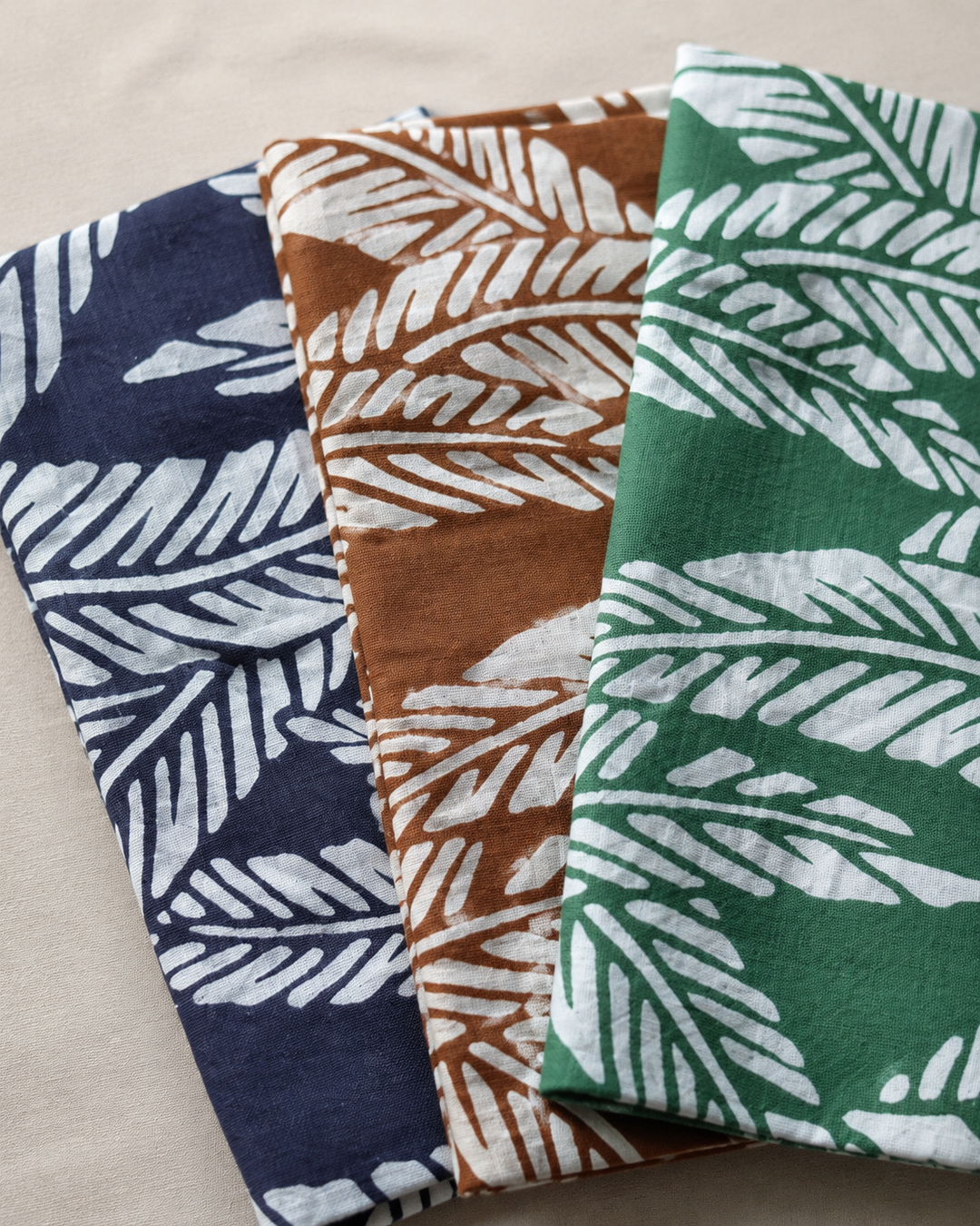 Close view of the folded navy, brown, and green Basho-pattern tenugui in soft indoor daylight.