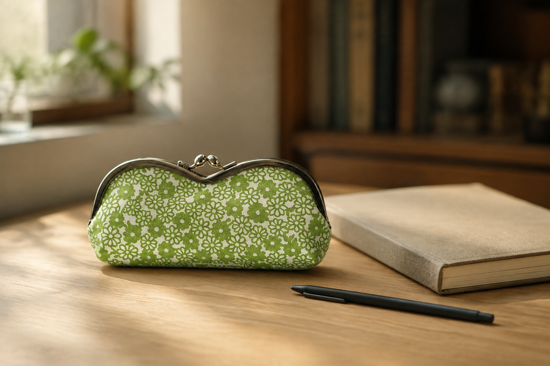 Yellow-green Tokyo Some-Komon eyeglass case beside a notebook and pen on an indoor desk.
