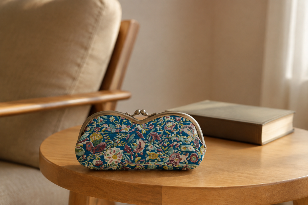 Turquoise Edo Sarasa eyeglass case on a small table beside an indoor reading chair.