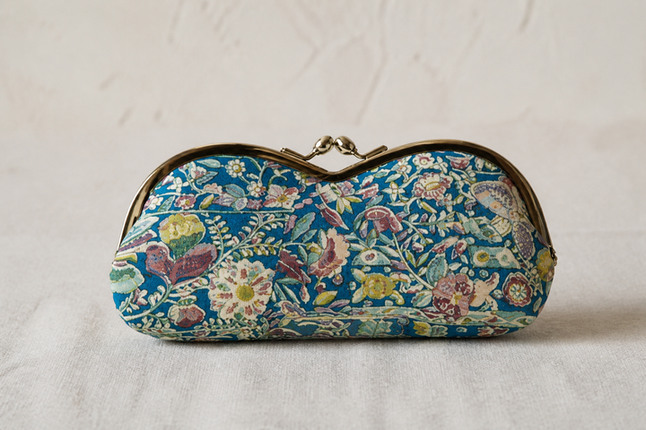 Close view of the flowers, foliage and birds on a turquoise Edo Sarasa eyeglass case in soft daylight.