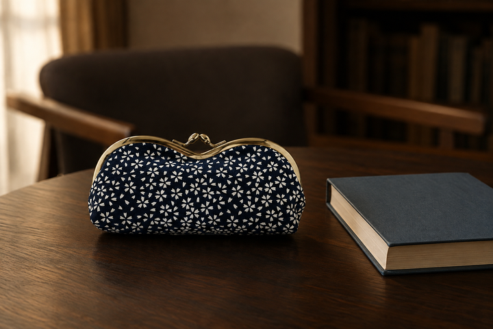 Navy Tokyo Some-Komon eyeglass case beside a closed book on an indoor reading table.