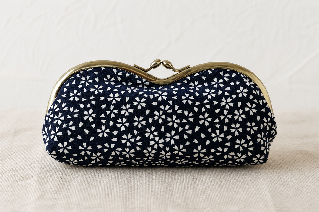 Close indoor view of the dense white cherry-blossom repeat on a navy Tokyo Some-Komon eyeglass case.