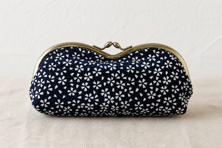 Close indoor view of the dense white cherry-blossom repeat on a navy Tokyo Some-Komon eyeglass case.