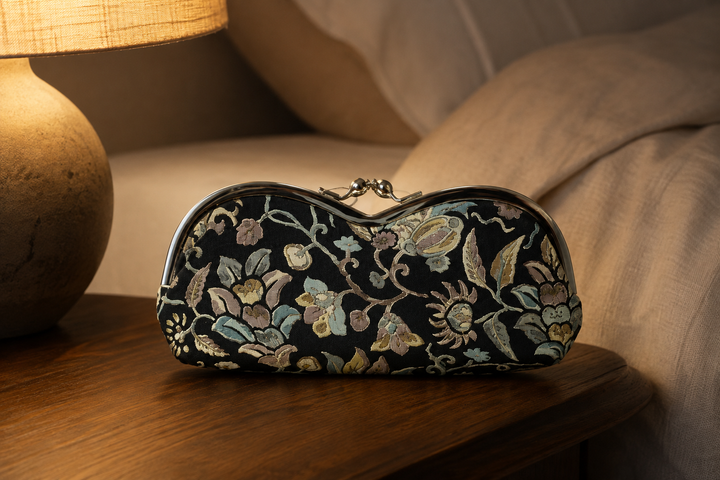 Black Edo Sarasa floral arabesque eyeglass case on a bedside table at the end of the day.