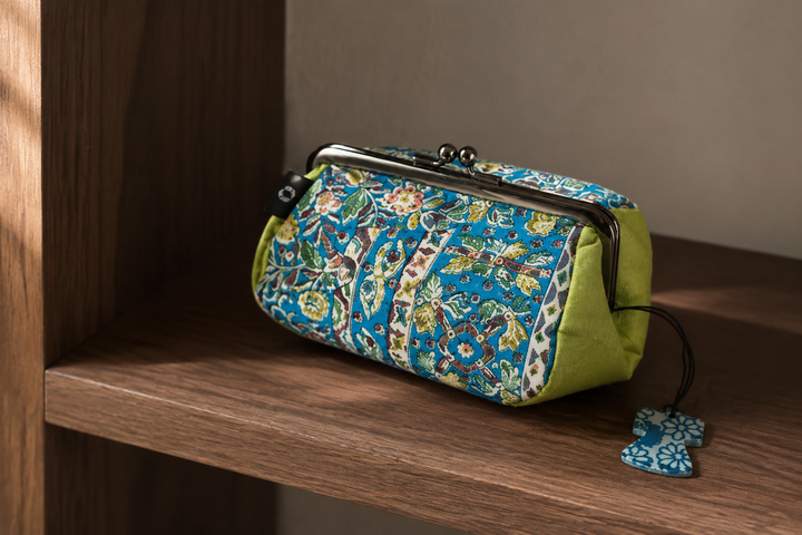 Close indoor view of the turquoise flower-and-bird Edo Sarasa pattern across the gathered silk pouch.
