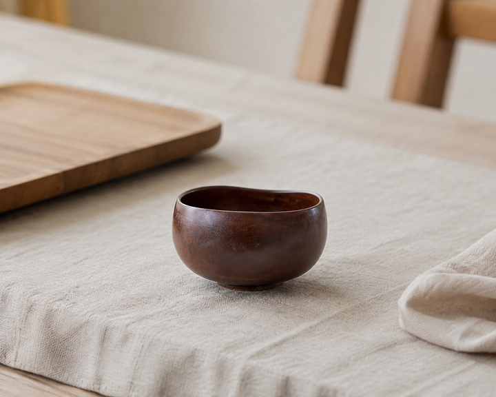 Bud: Lilac lacquerware vessel beside pale linen and natural wood at breakfast.
