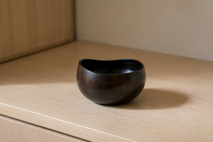 Close view of the sesame-black lacquered vessel on pale wood under soft indoor light, revealing subtle grain and sheen.