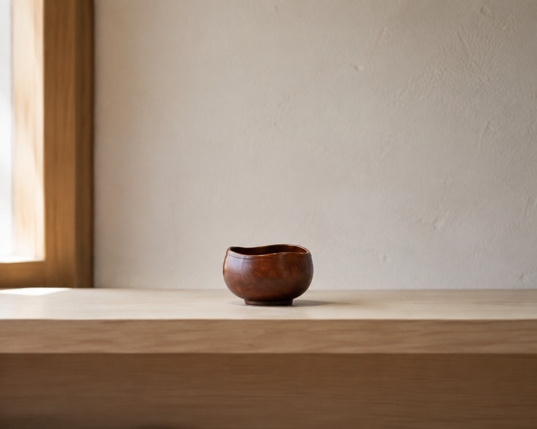 Bud: Mimosa lacquer vessel displayed with open space on a light wood shelf.