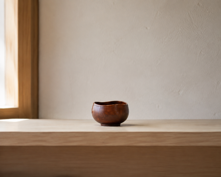Bud: Mimosa lacquer vessel displayed with open space on a light wood shelf.