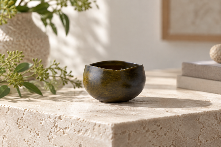Bud: Olive standing on pale stone with its rounded body and gently irregular rim visible.