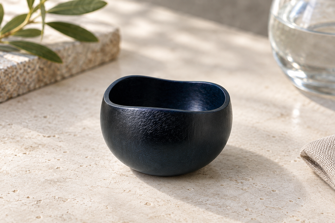 A close view of the empty dark Hyacinth vessel on pale stone, showing its opening and textured lacquer surface.