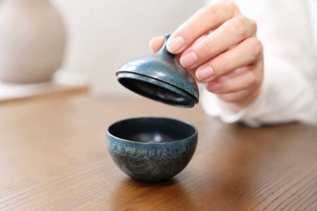 Clean dry adult hands gently lifting the tapered lid from the rounded blue-green Bulb: Hyacinth body.