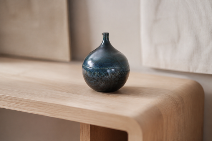 Closed blue-green Bulb: Hyacinth lacquerware on a quiet pale-wood shelf in soft indoor light.