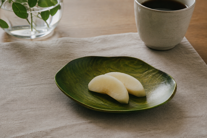 RIN 5.0 Olive lacquerware plate with a small breakfast fruit serving beside a cup and neutral linen.