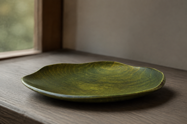 Empty RIN 5.0 Olive plate in soft indirect window light, revealing its low rim and lacquered wood grain.