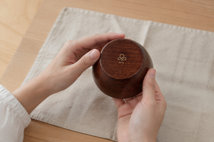 Adult hands briefly turning the clean empty RIN Bowl S Lilac to reveal its photographed YUIYU base mark.