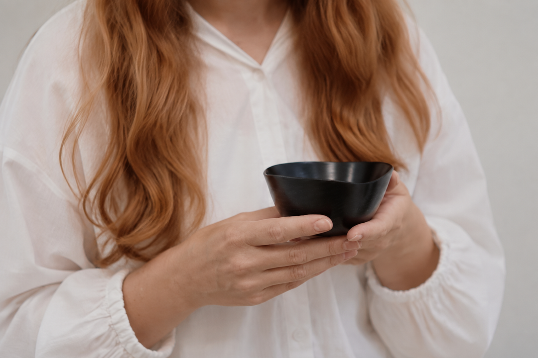 Adult hands holding the empty RIN Bowl S Hyacinth close to the body to show its compact scale.