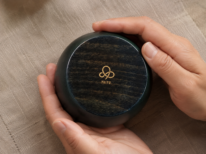 Adult hands briefly supporting the inverted RIN Bowl S Hyacinth to reveal the small YUIYU mark underneath.