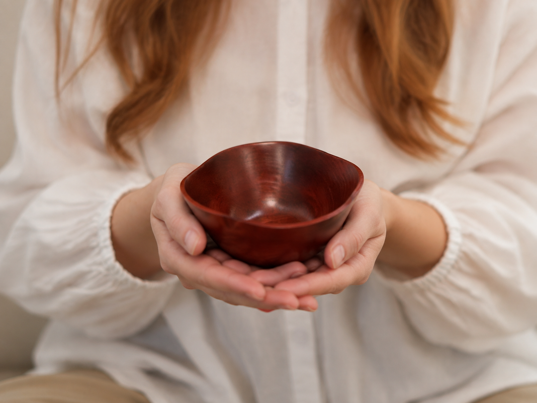Adult hands supporting the empty RIN Bowl M Berry from below to show its compact scale.