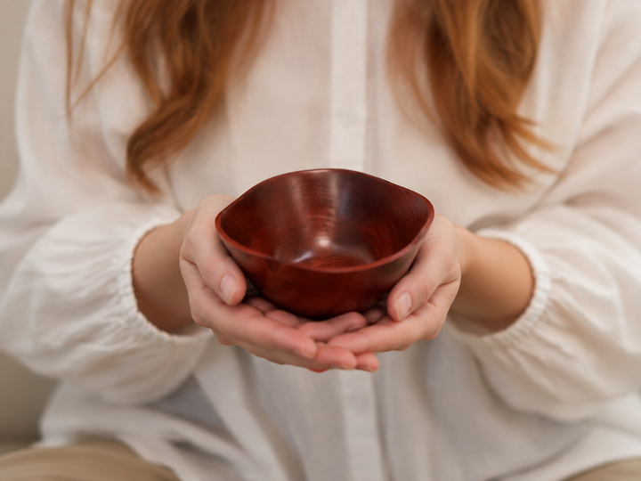 Adult hands supporting the empty RIN Bowl M Berry from below to show its compact scale.