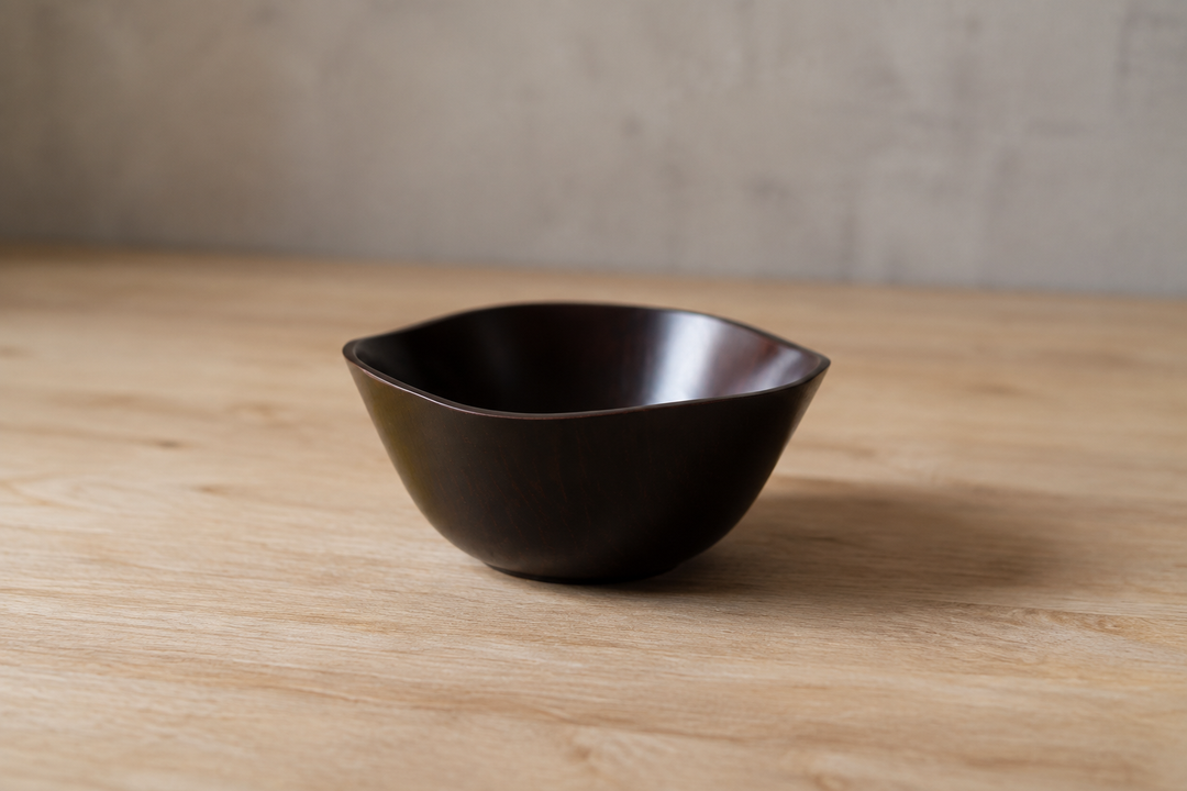 Empty RIN Bowl M Lilac with its undulating rim in full view on a stable pale wood surface.