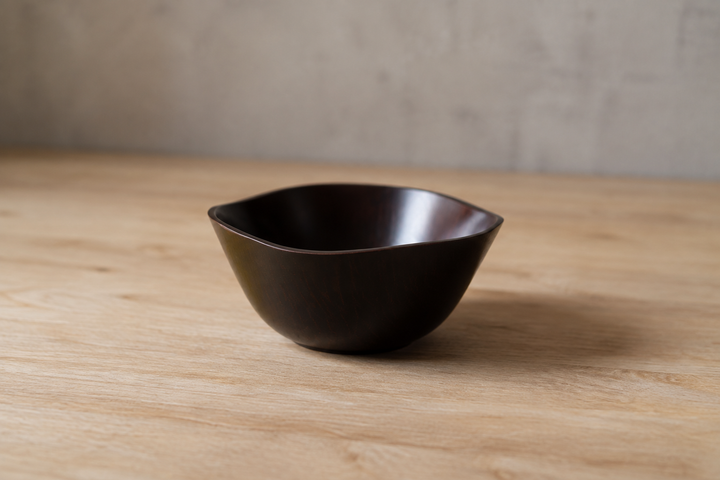 Empty RIN Bowl M Lilac with its undulating rim in full view on a stable pale wood surface.