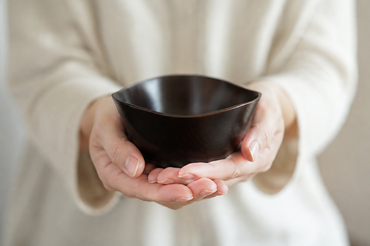 Empty RIN Bowl M Lilac supported from below between two adult hands.