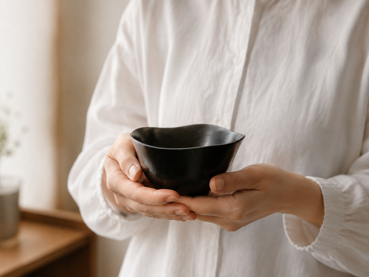 Adult holding the empty RIN Bowl M Sesame gently in both hands, revealing its 120-millimeter scale and curved wall.