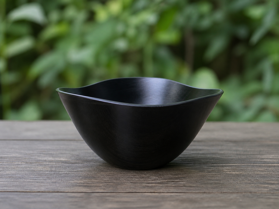 RIN Bowl M Sesame resting temporarily on a stable shaded outdoor table with soft greenery in the distance.
