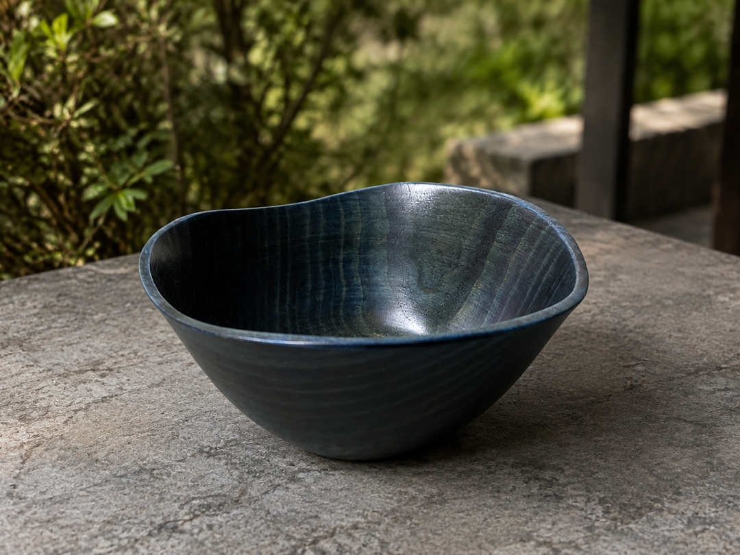 Empty RIN Bowl M Hyacinth resting briefly on a level shaded terrace table with soft greenery beyond.