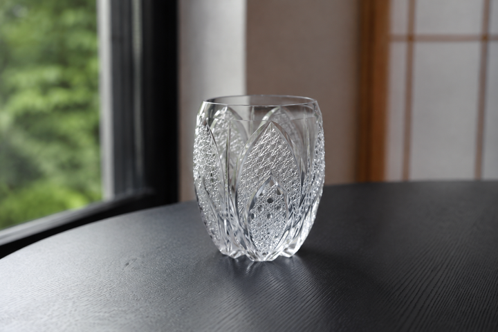 SHIROHANA: Clear standing empty on a stable dark table as soft side light reveals its petal-like cuts.