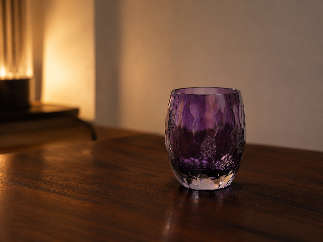 Purple Edo Kiriko glass on a quiet dark-wood table in warm evening side light.