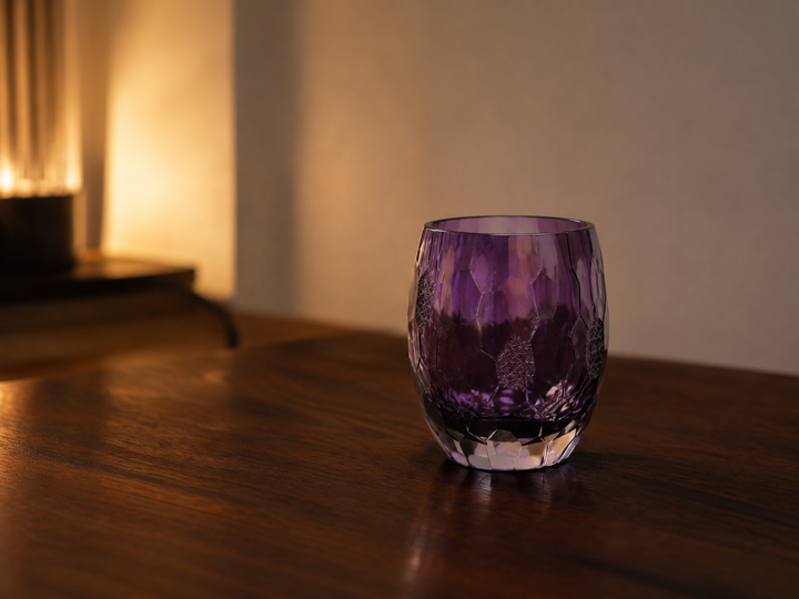 Purple Edo Kiriko glass on a quiet dark-wood table in warm evening side light.
